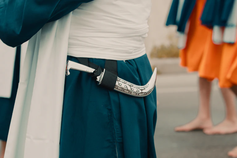A kirpan at the waist of a person dressed in ceremonial clothing