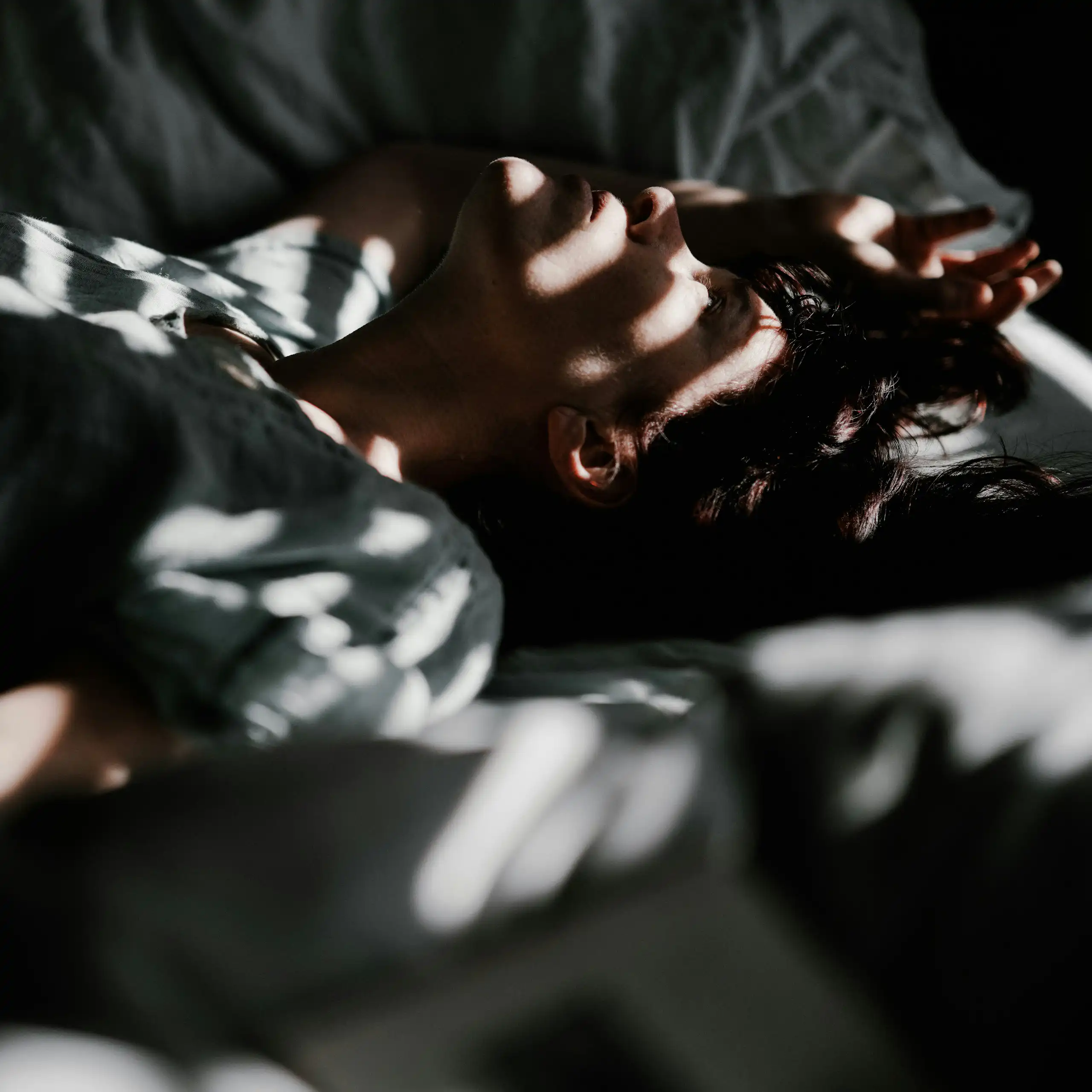 Un homme est couché dans un lit dans la pénombre.