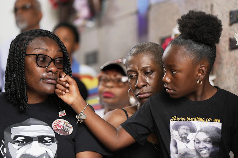 A group of family members are mourning and consoling each other at a vigil.