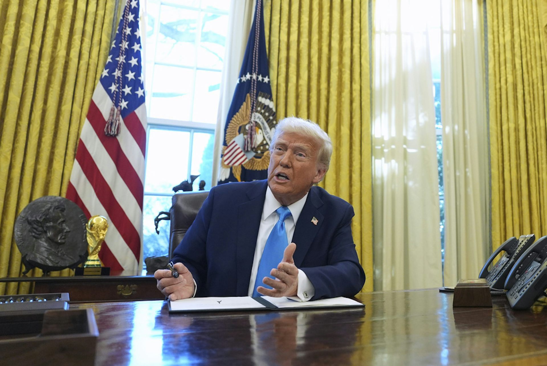 A man in a suit sits at a desk.