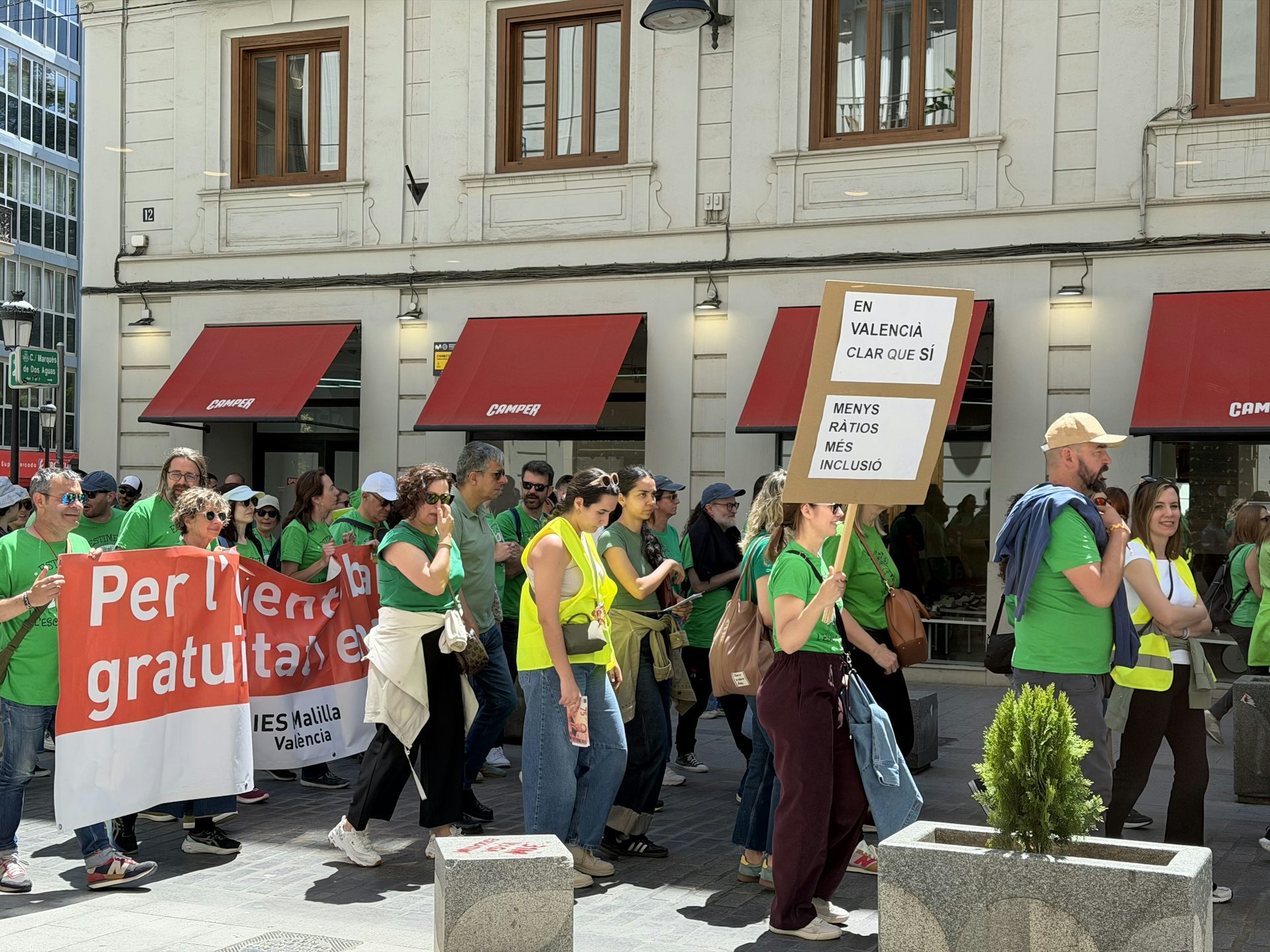 Gent vestida amb una samarreta verda al carrer. Porten un cartell on es llig: "Més ràtios, més inclusió".