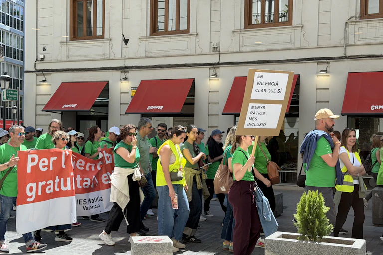 Gent vestida amb una samarreta verda al carrer. Porten un cartell on es llig: "Més ràtios, més inclusió".