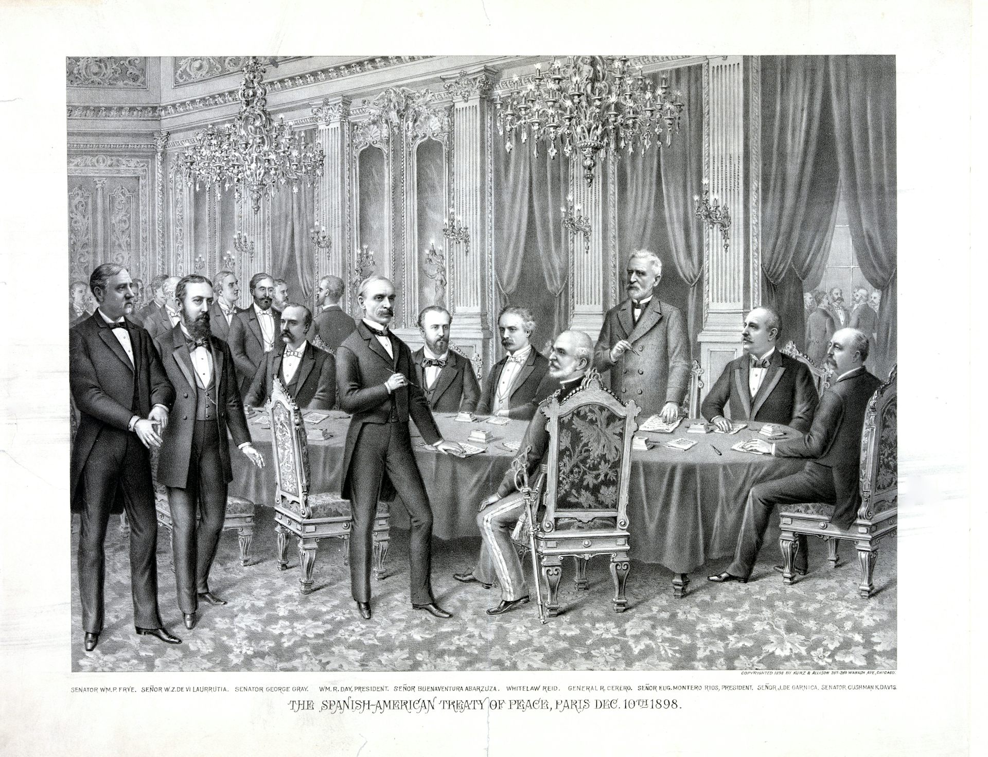 Pictured are several people in suits standing around a table