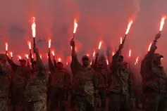 El homenaje de Zelensky a los nacionalistas en tiempos de guerra refuerza la alianza de Ucrania con Polonia 2 Un grupo de hombres con uniformes militares sostienen cohetes encendidos.