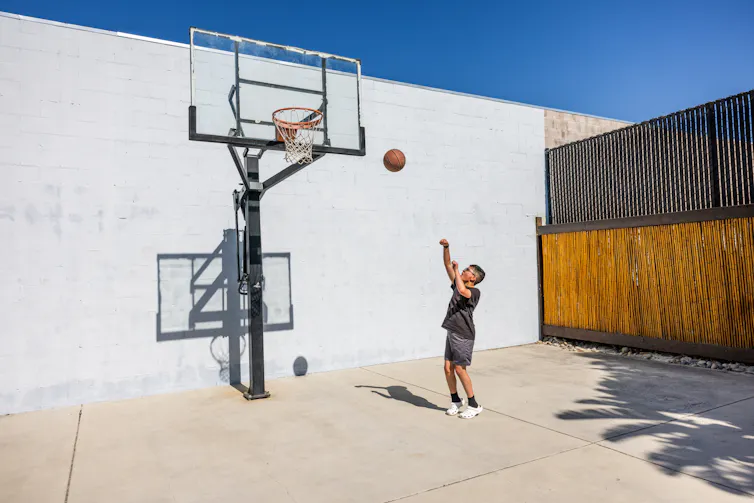boy shooting baskets alone