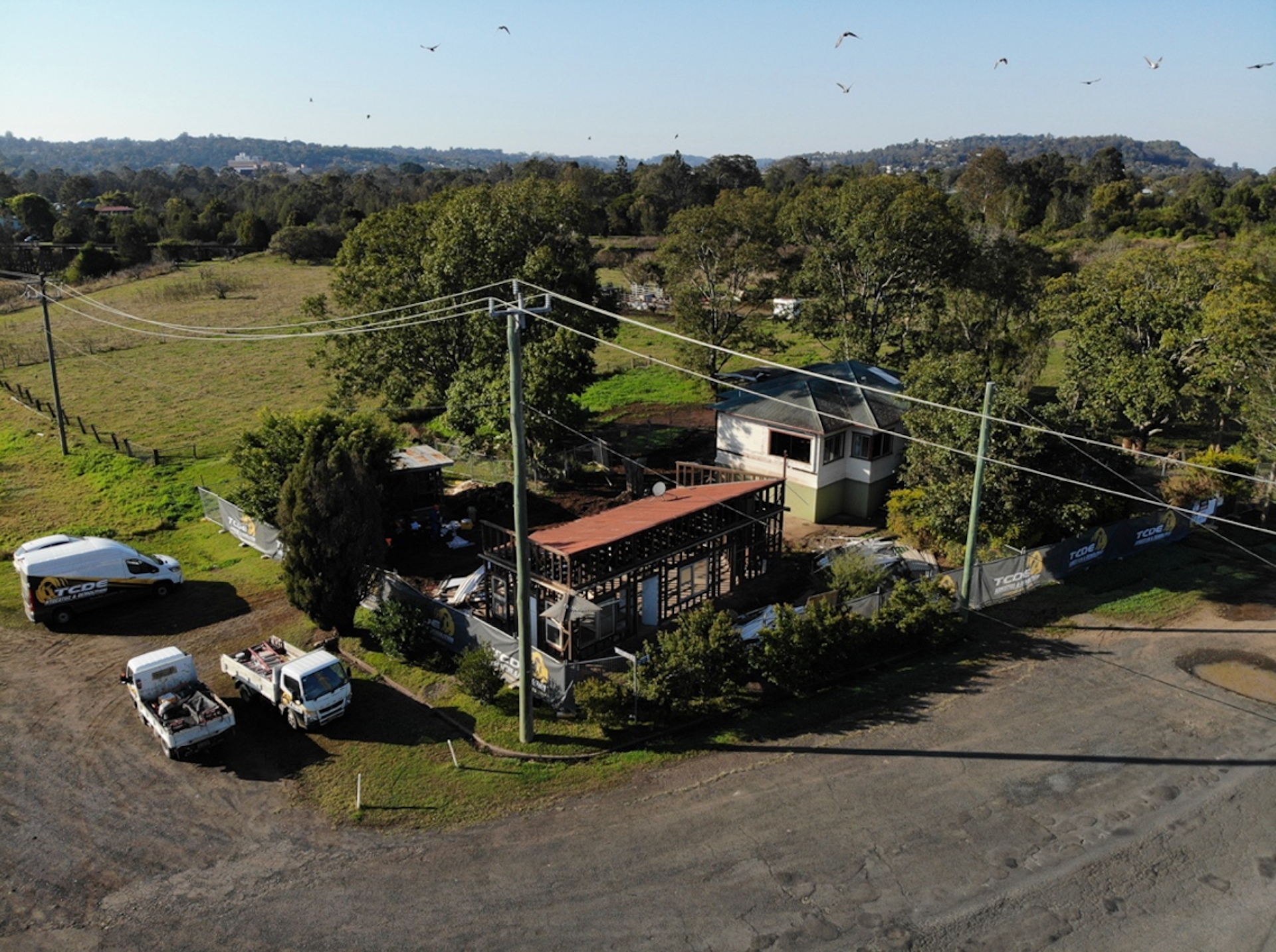 An aerial photo of two houses on a green hill.