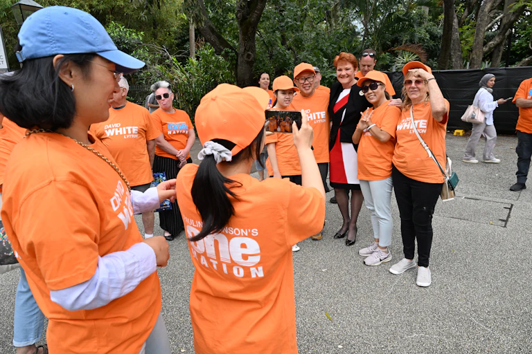 One Nation supporters in orange t-shirts pose for a photo with Pauline Hanson