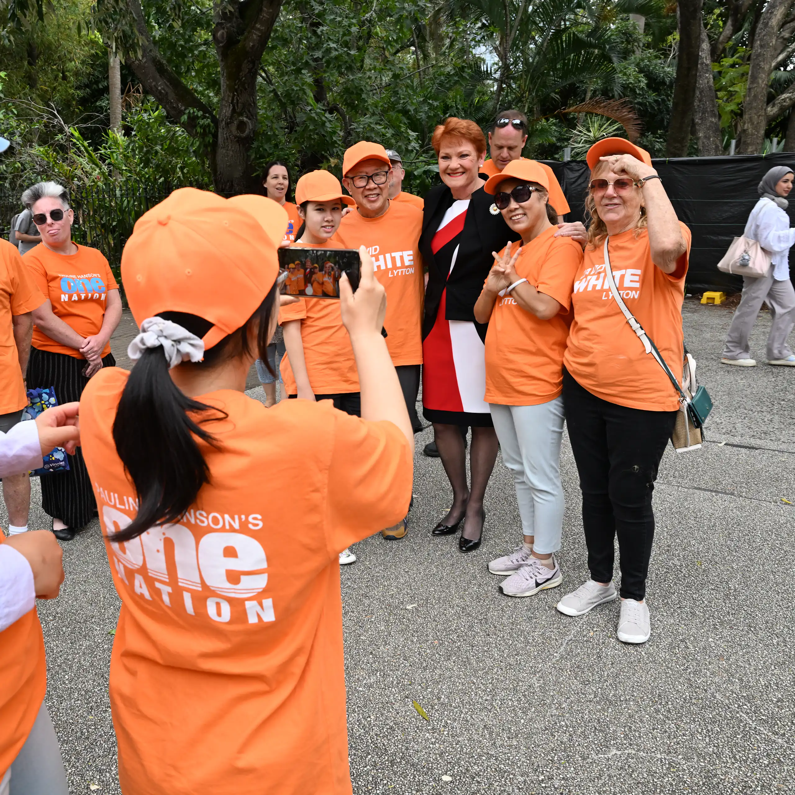 One Nation supporters in orange t-shirts pose for a photo with Pauline Hanson