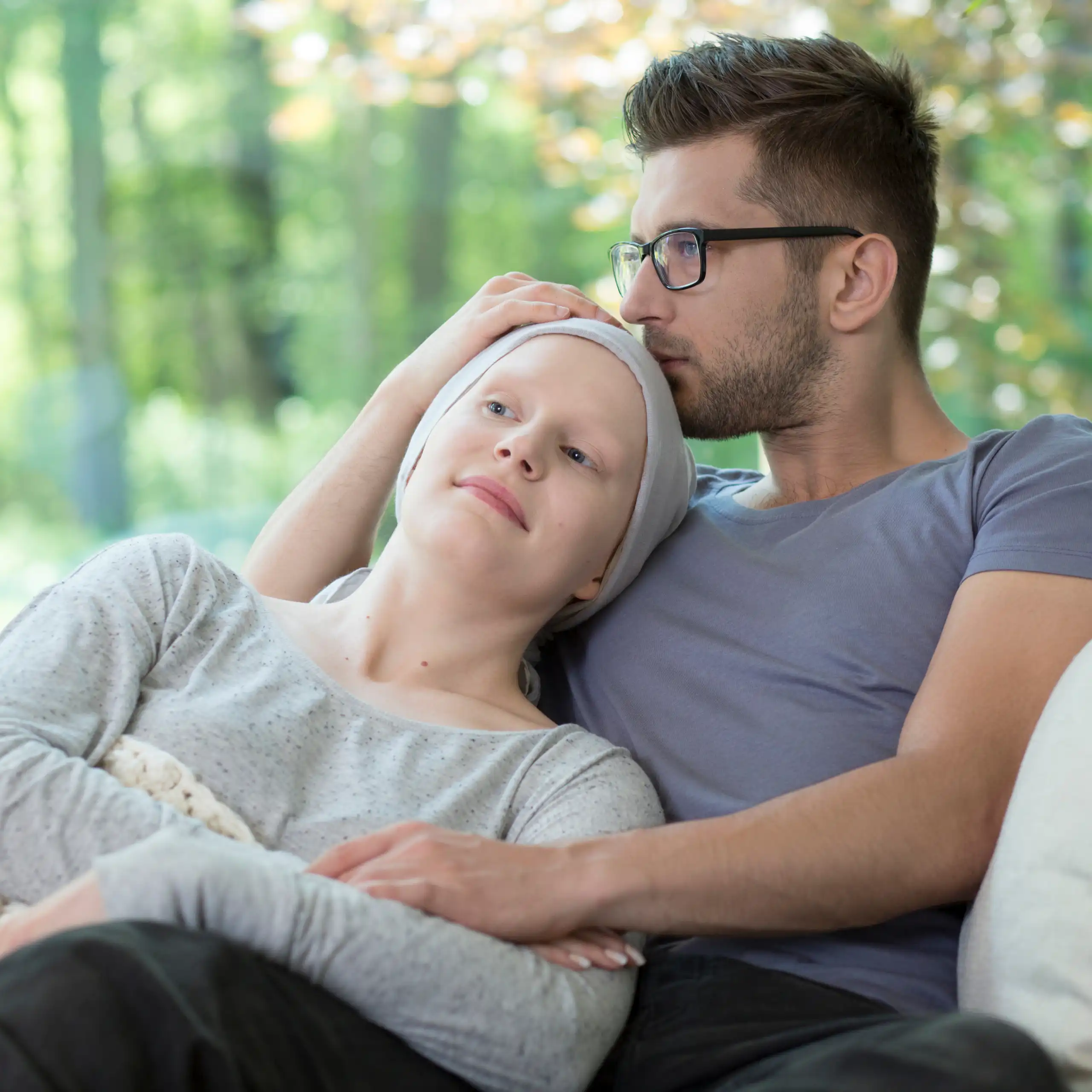 Un homme enlace une femme qui semble malade sur un canapé.