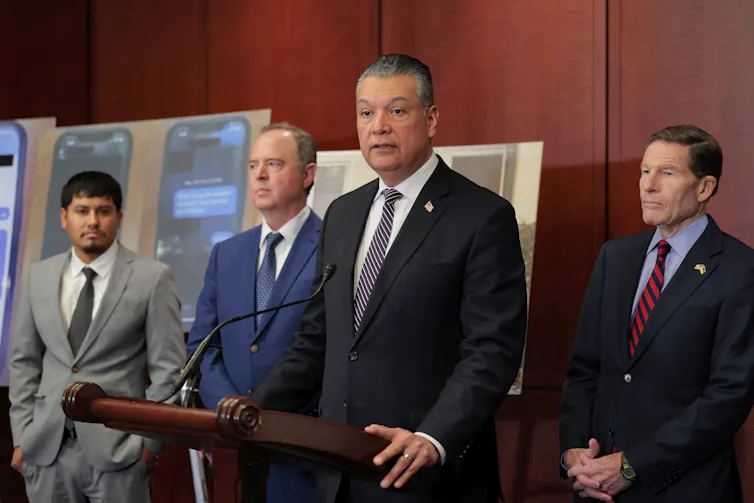 Tanto los demócratas como los republicanos donan millones a universidades con fines específicos, pero no de la misma manera 2 Cuatro hombres visten trajes y están juntos en un podio de madera.
