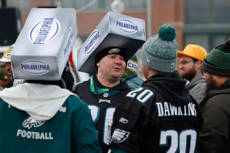 Men in football jerseys wear cardboard boxes for Philadelphia cream cheese on their heads