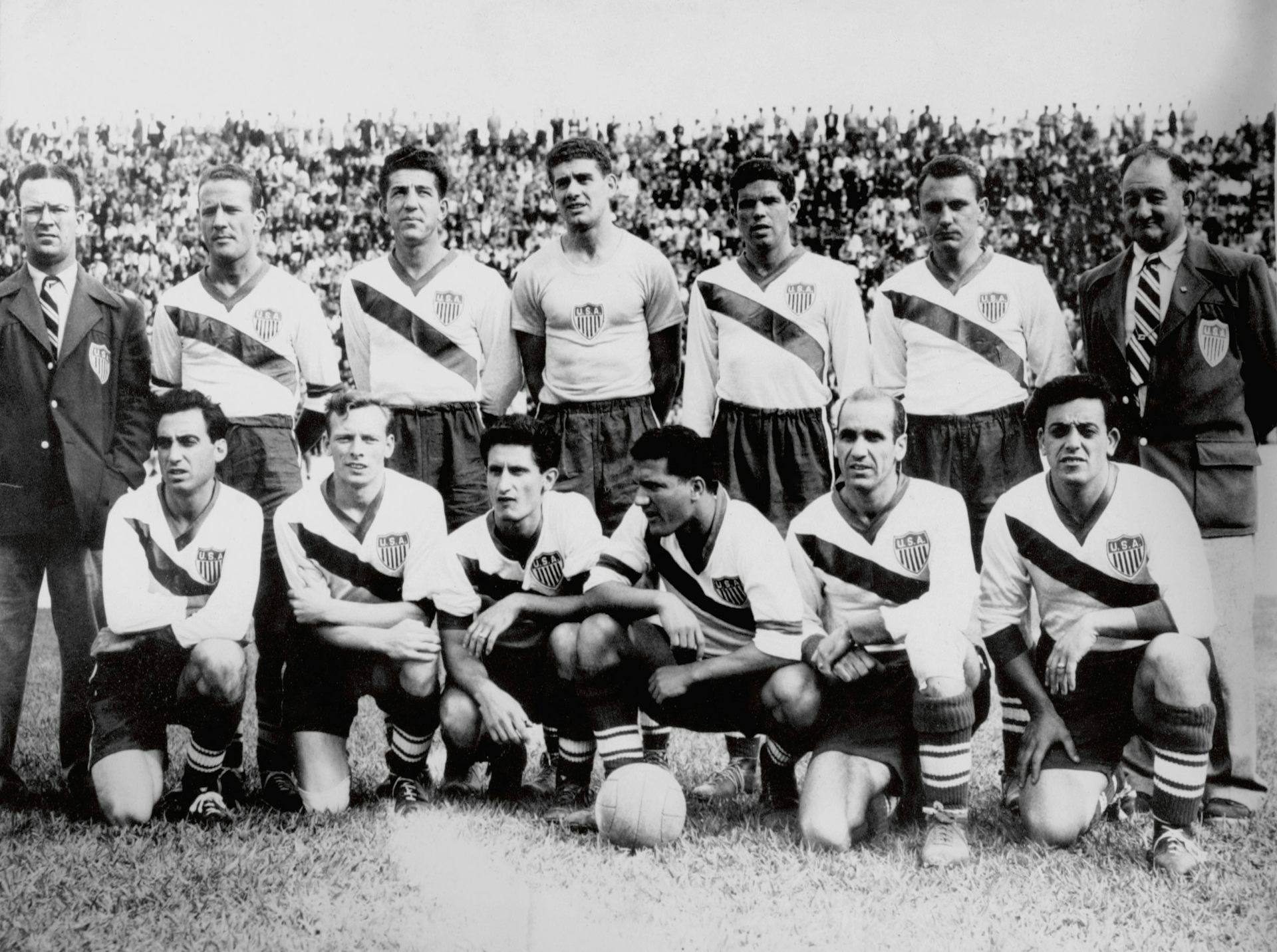 A black and white photo shows a group of men in soccer jerseys.