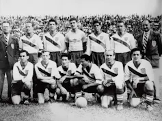 A black and white photo shows a group of men in soccer jerseys.