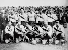 A black and white photo shows a group of men in soccer jerseys.
