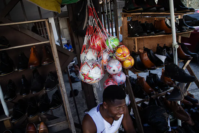 A man sits ion front of a bag of balls.