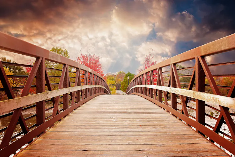 A wooden footbridge with a landscape beyond