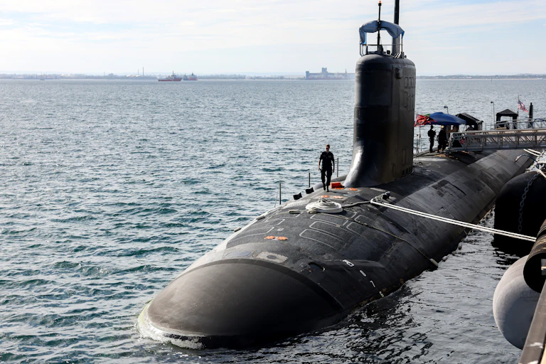 A submarine half submerged in the ocean with a naval office walking on top