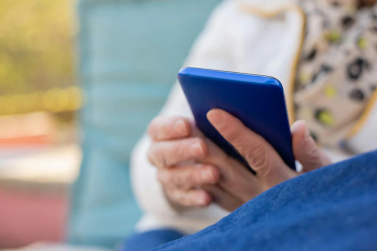 an older woman holding a blue mobile phone