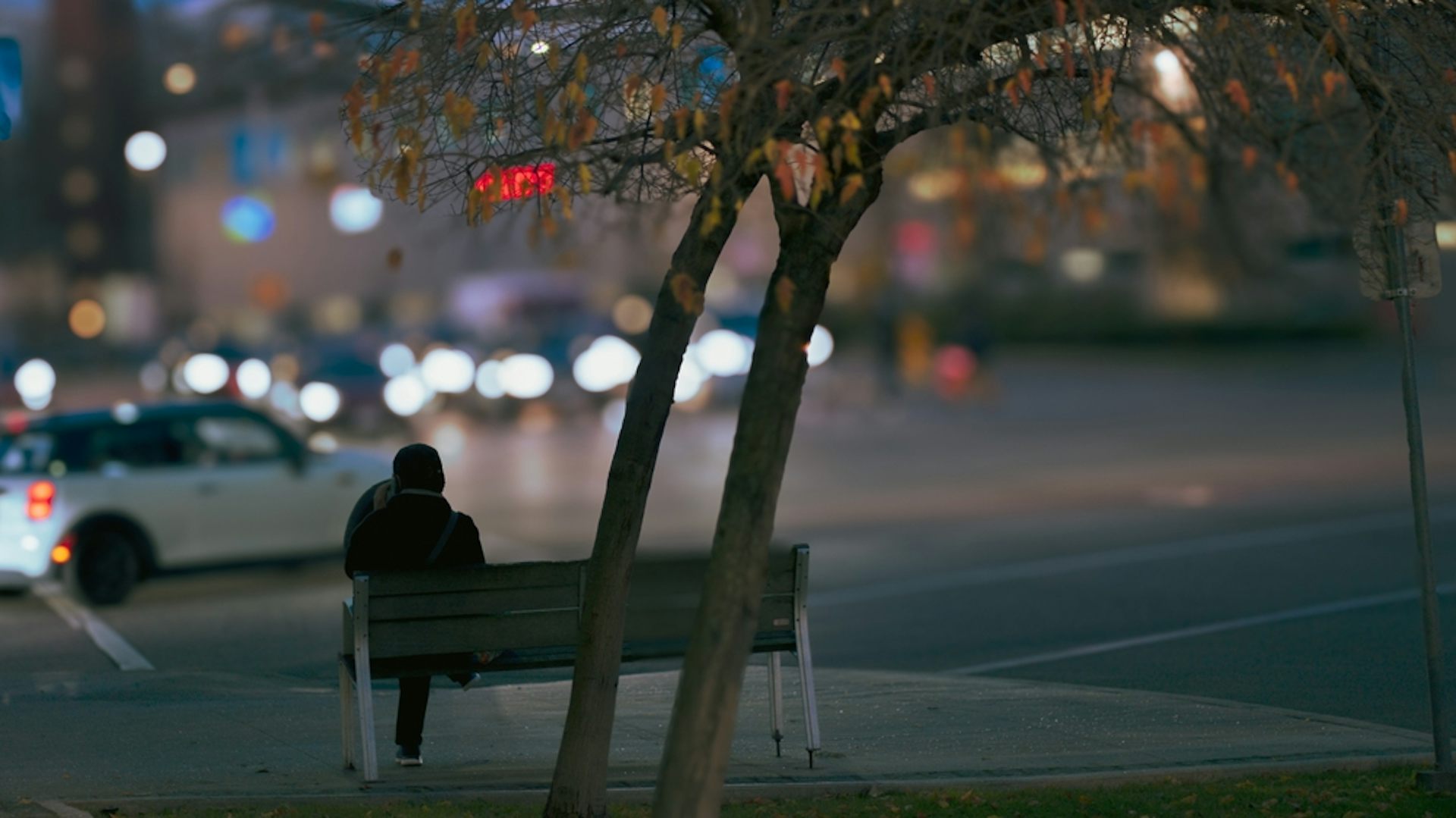 Une personne assise sur un banc, dans une ville