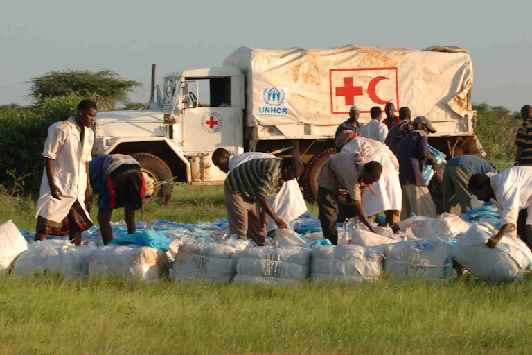 Men arranging packages on the ground in front of a white truck