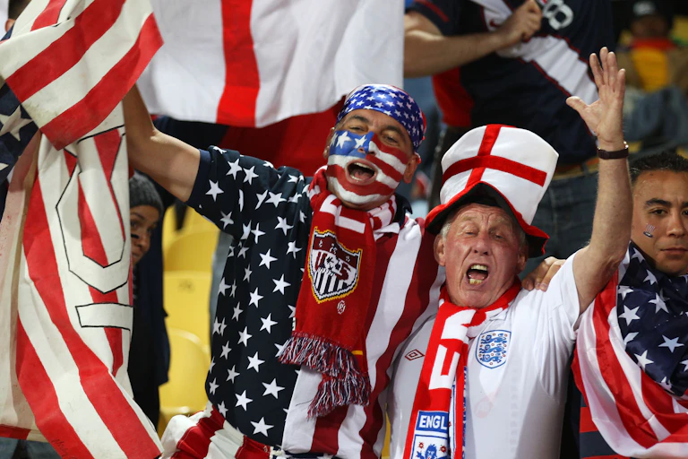 Two soccer fans wear patriotic English and American clothing and face paint.