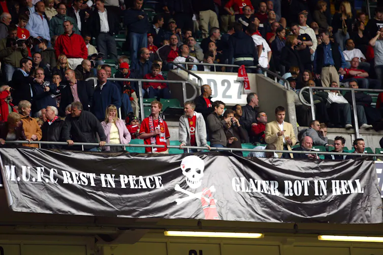 A large banner is seens saying 'MUFC Rest in Peace. Glazer rot in hell.