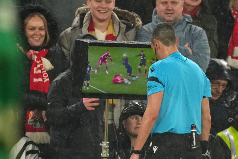 Um árbitro analisa as imagens do monitor de vídeo durante uma partida de futebol da Liga dos Campeões da Europa.