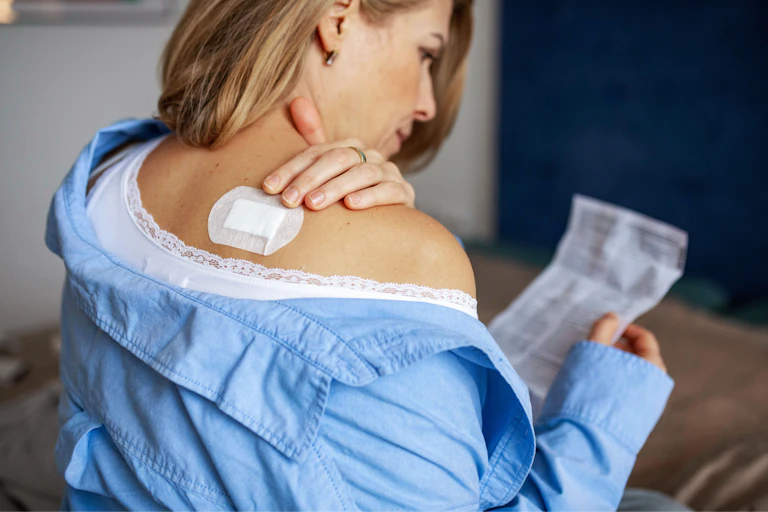 Women with her back to camera, with a estradiol patch on her shoulder
