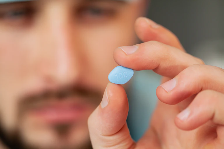 A man holds a sildenafil (Viagra) pill in his fingers.