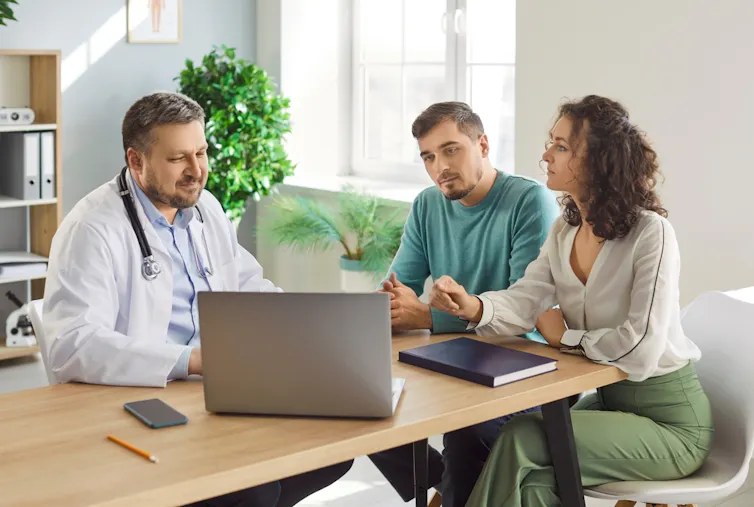 A couple at a fertility clinic speak with a doctor.