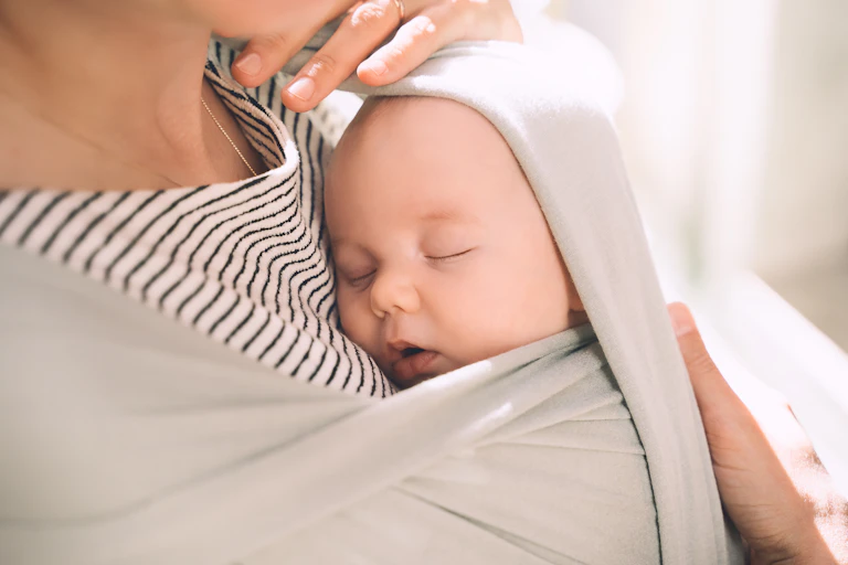 Close up of woman carrying baby in a chest sling
