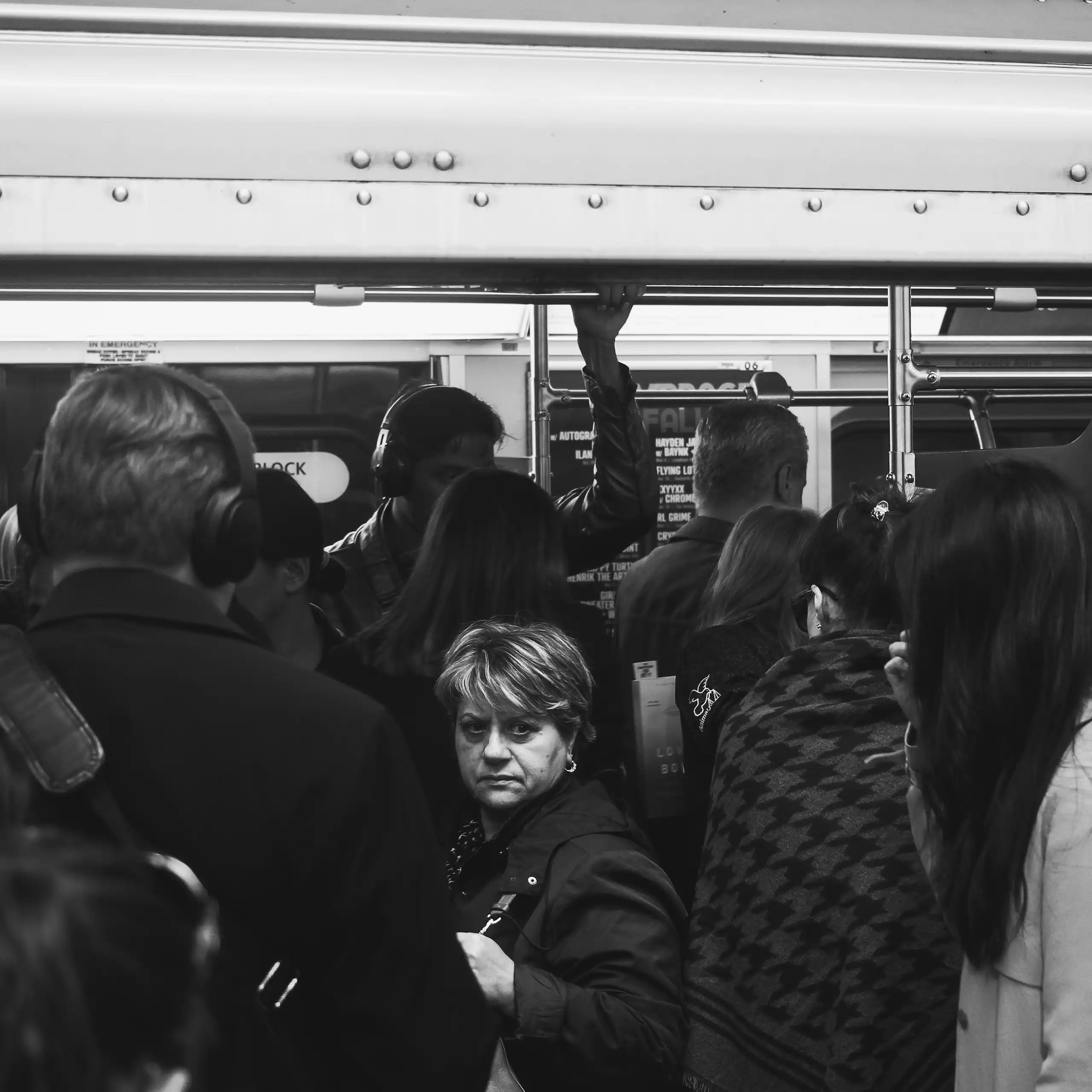 A group of people packed into a subway car with an older woman looking back.