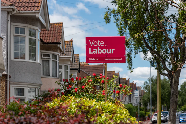 solitary labour poster in a front garden of a leafy street.