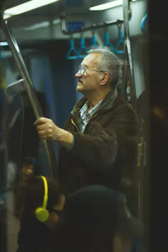 Un anciano se aferra a una valla de tránsito.