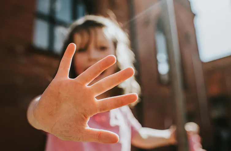 Young girl holding her hand up to the camera