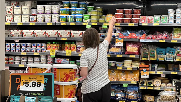 a person reaching for a product in a supermarket fridge