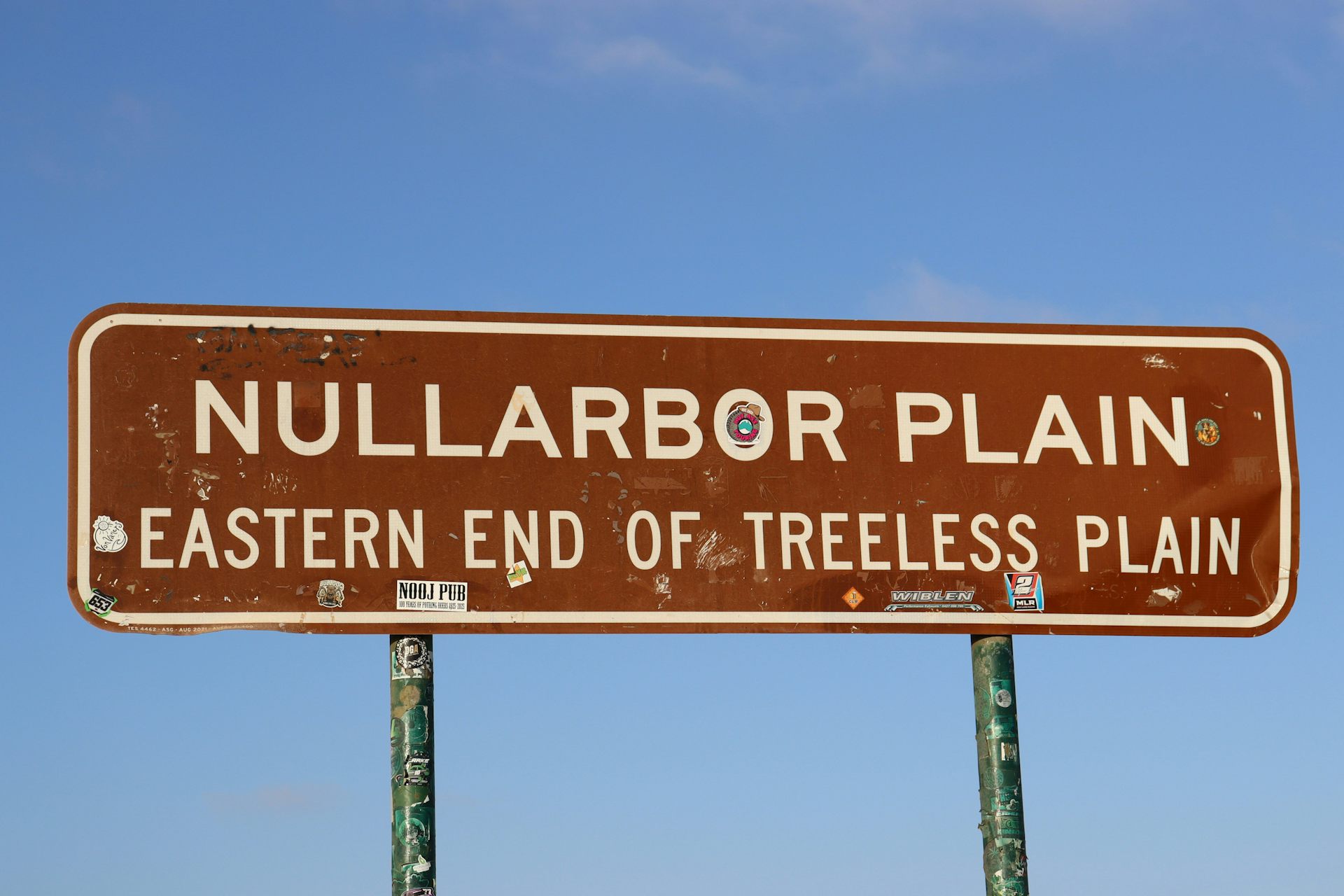 A brown sign signalling the Nullarbor Plain against a blue sky.