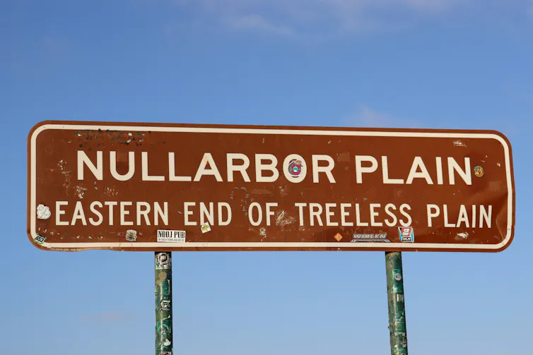 A brown sign signalling the Nullarbor Plain against a blue sky.