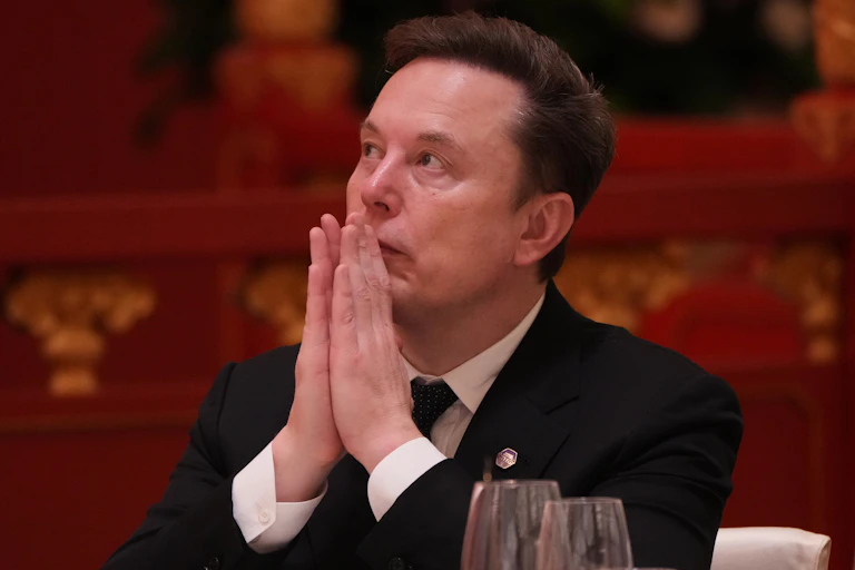 Elon Musk with his hands held up to his mouth