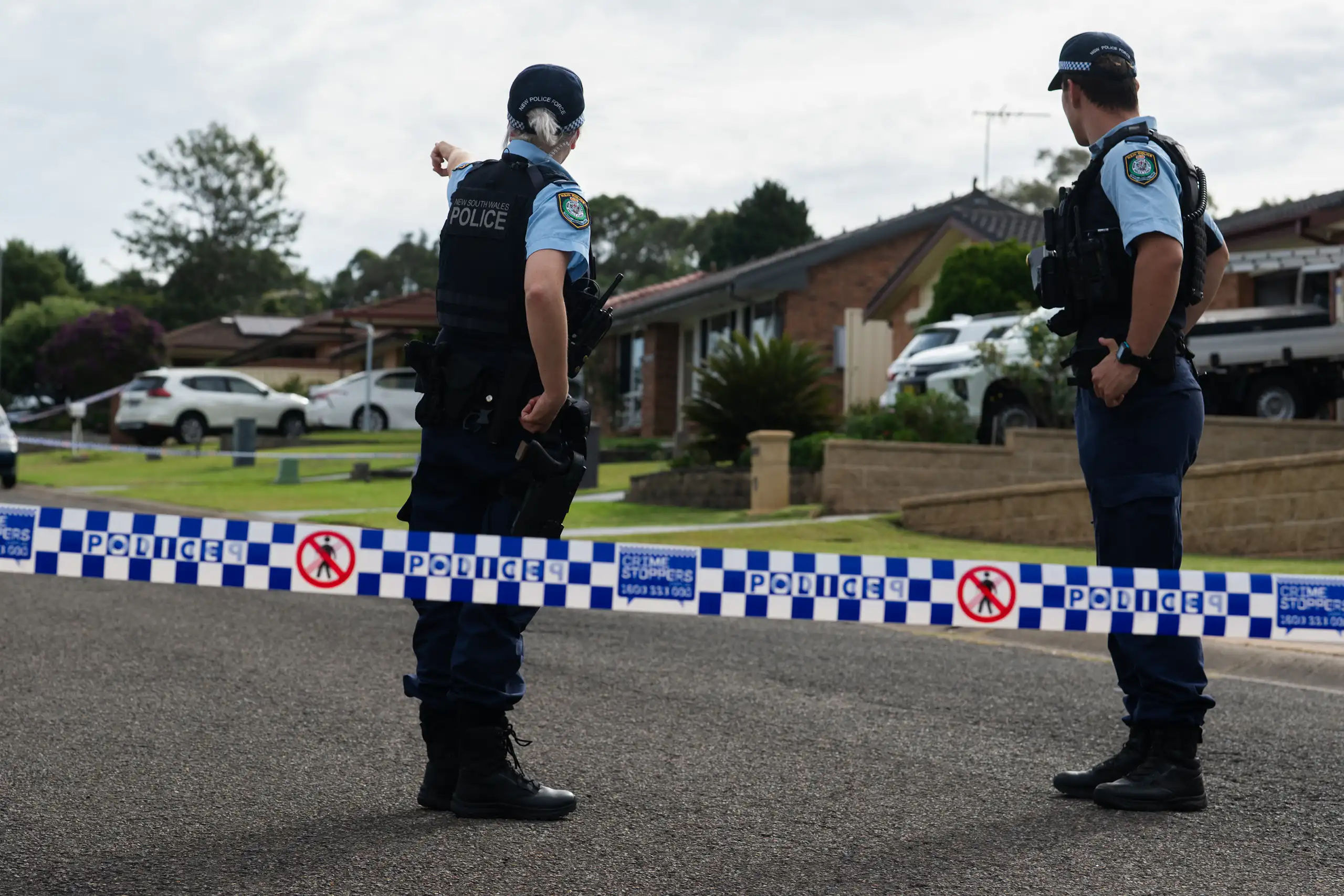 Two NSW police are seen from behind on a residential street in NSW, 2026.