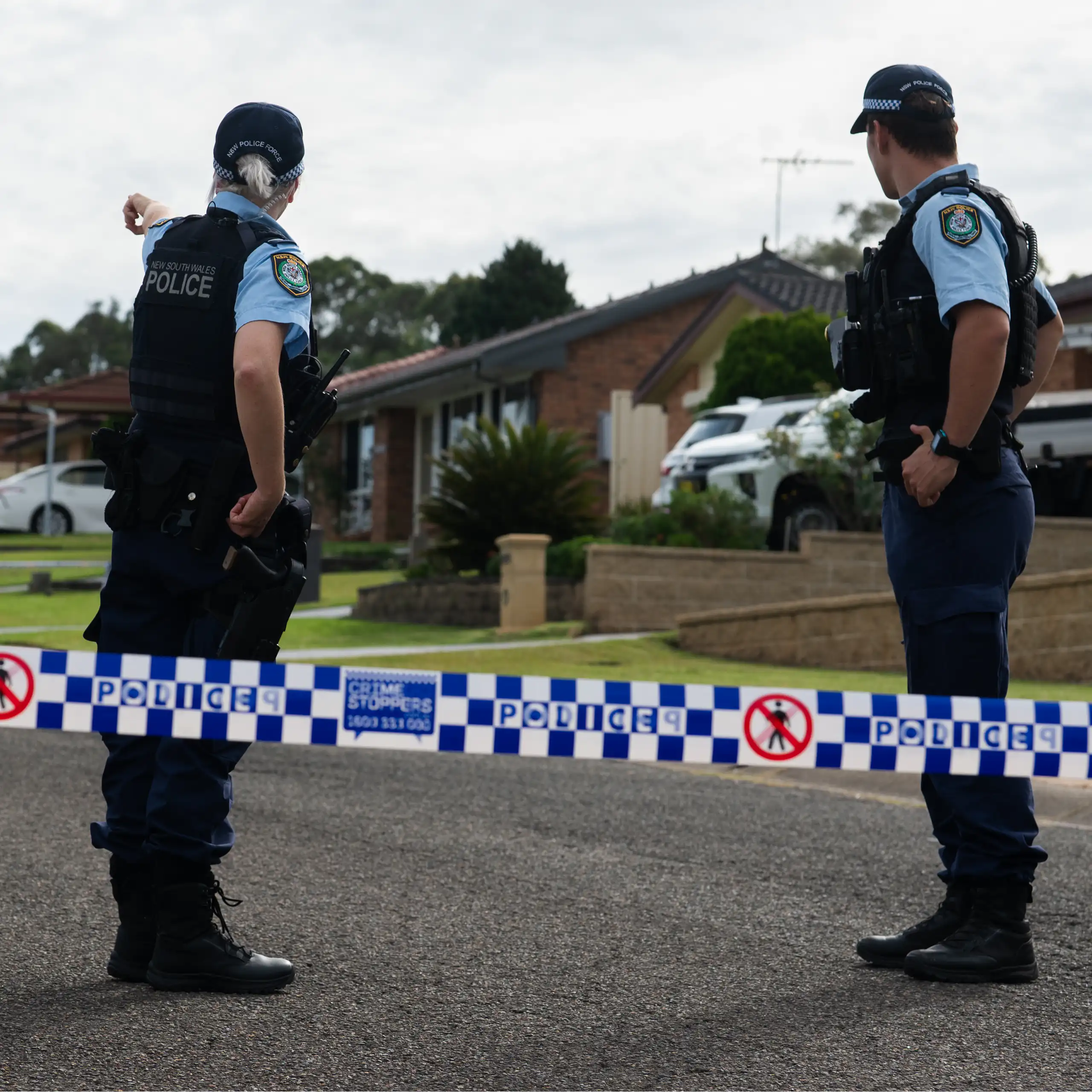 Two NSW police are seen from behind on a residential street in NSW, 2026.