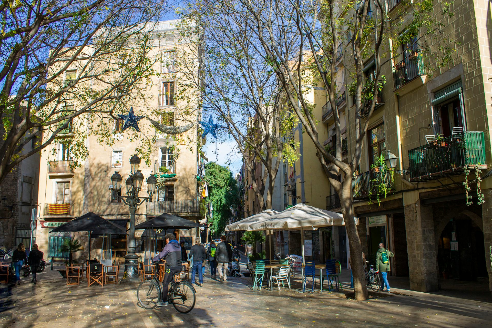 Plaza de una ciudad con árboles, sombrillas y una bicicleta.