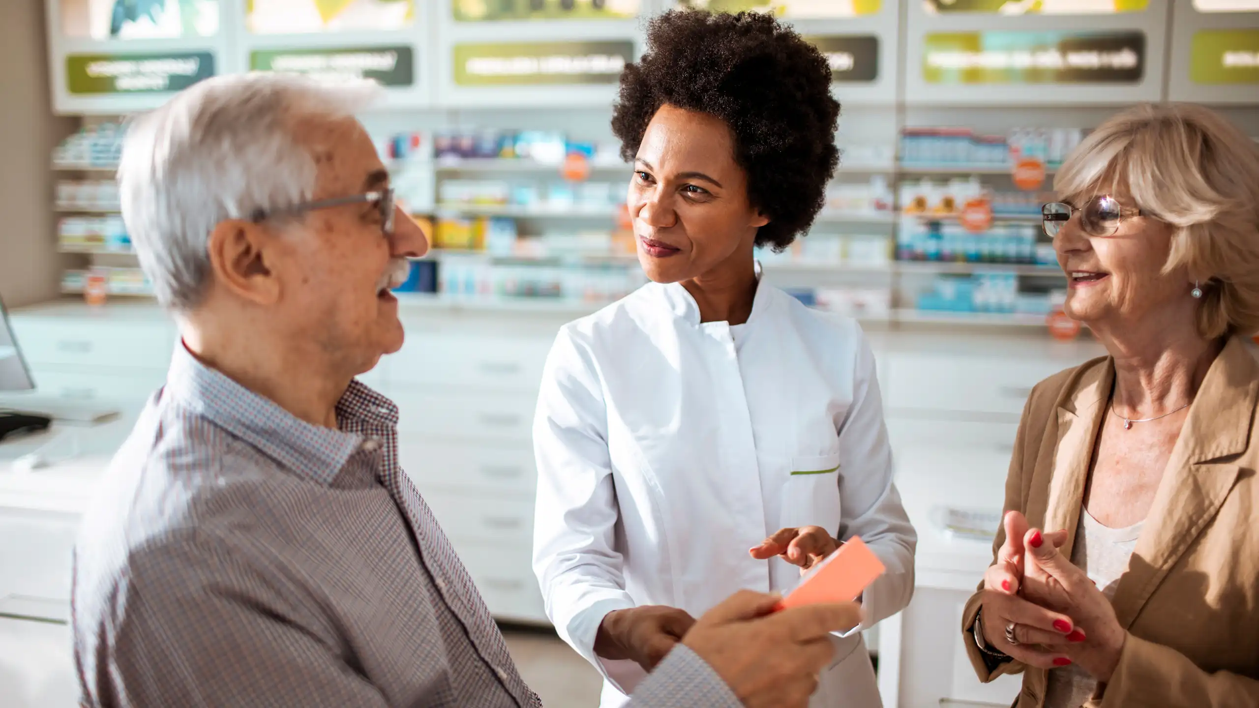 Un couple de personnes âgées prennent conseil auprès de leur pharmacienne.