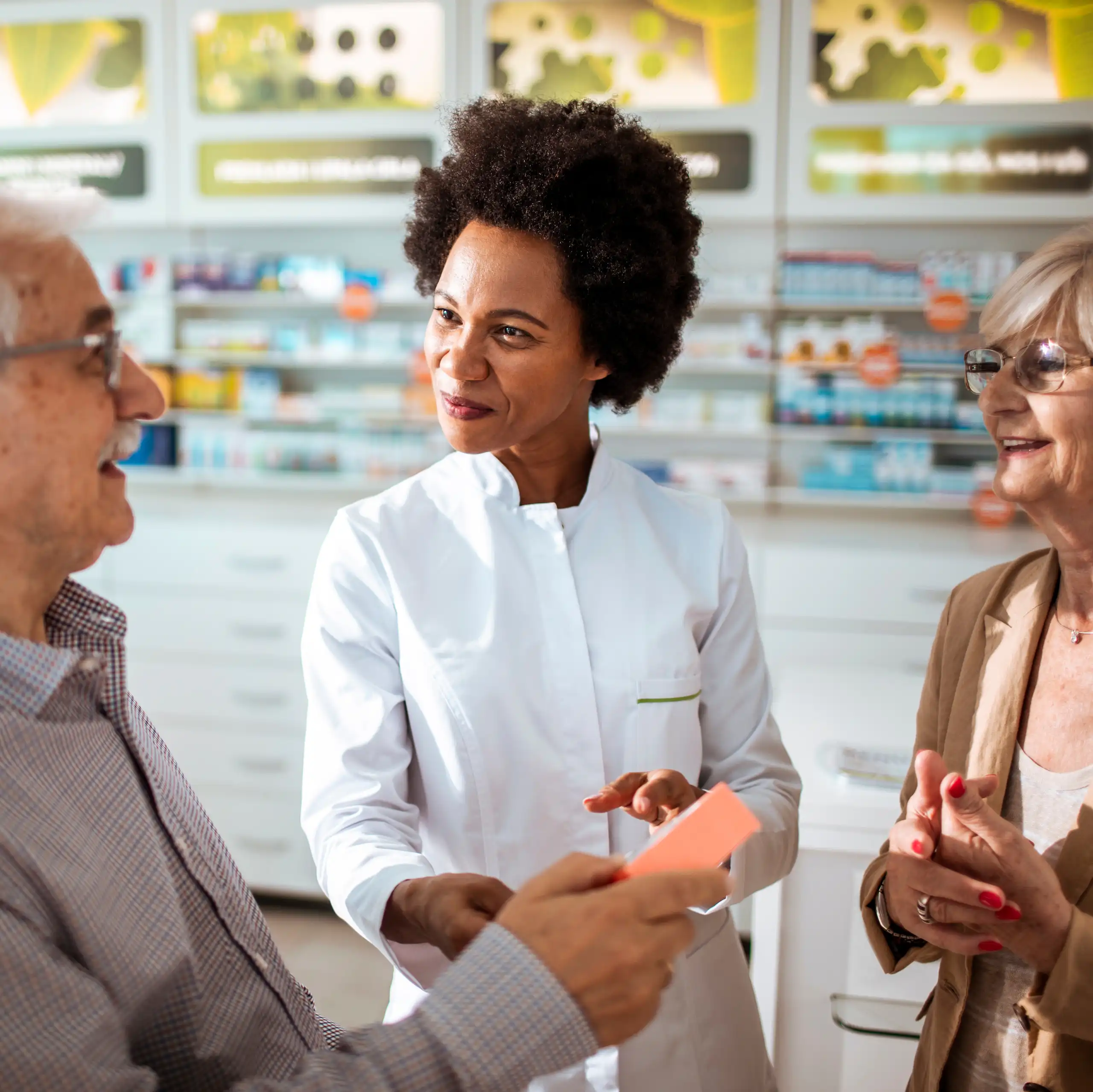 Un couple de personnes âgées prennent conseil auprès de leur pharmacienne.