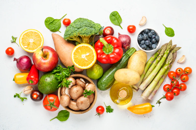An assortment of fruits and vegetables on a light grey background.