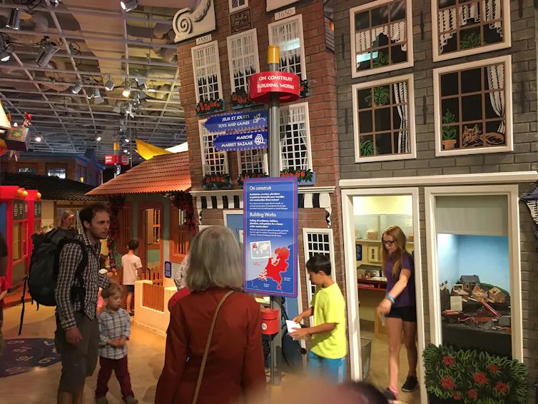 Un día en el museo: cómo seguir las pautas de los niños para apoyar la curiosidad intergeneracional 3 Se vio a adultos y niños luchando alrededor de la exhibición del museo.