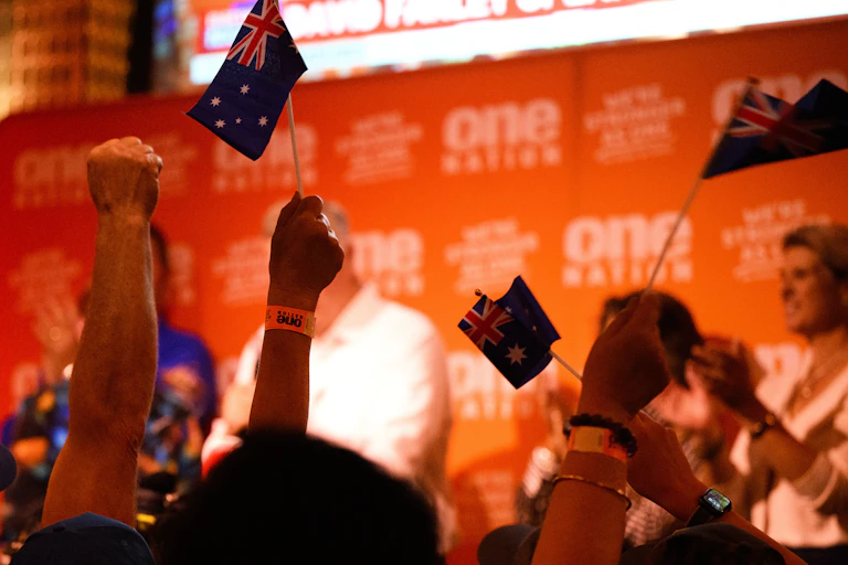 Fists and flags in the air at a One Nation election night party after the Farrer by-election