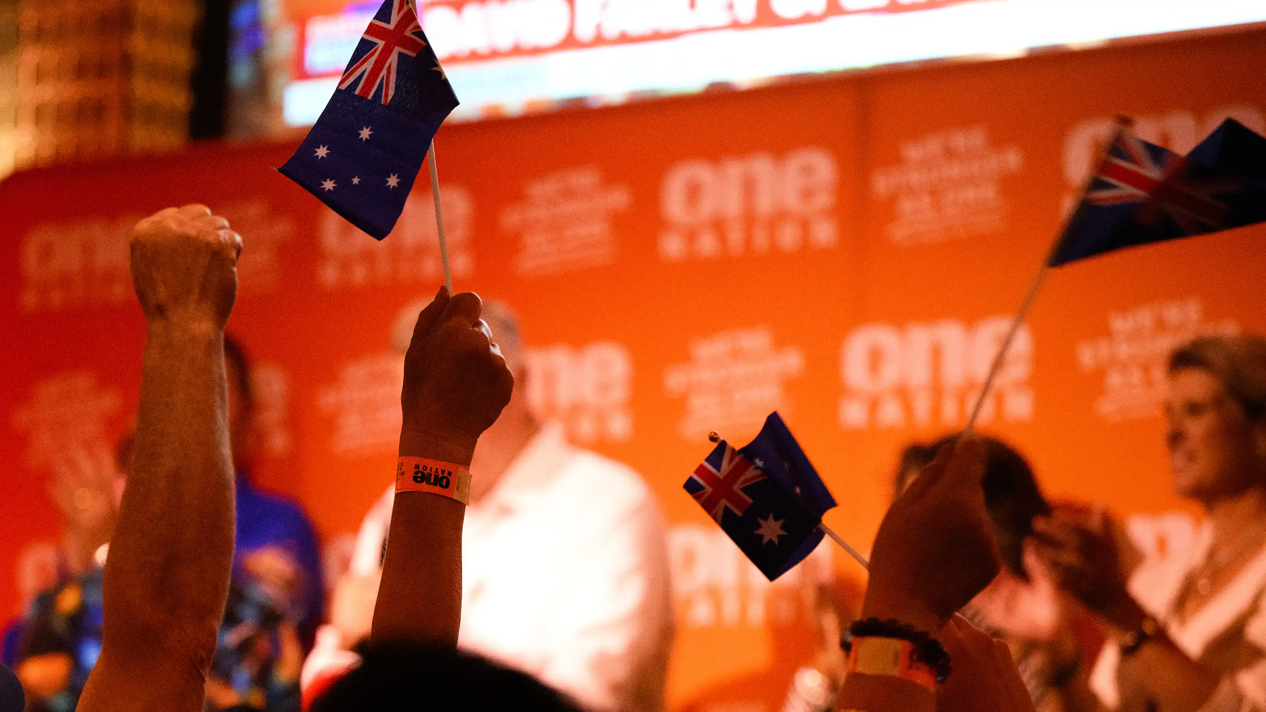 Fists and flags in the air at a One Nation election night party after the Farrer by-election