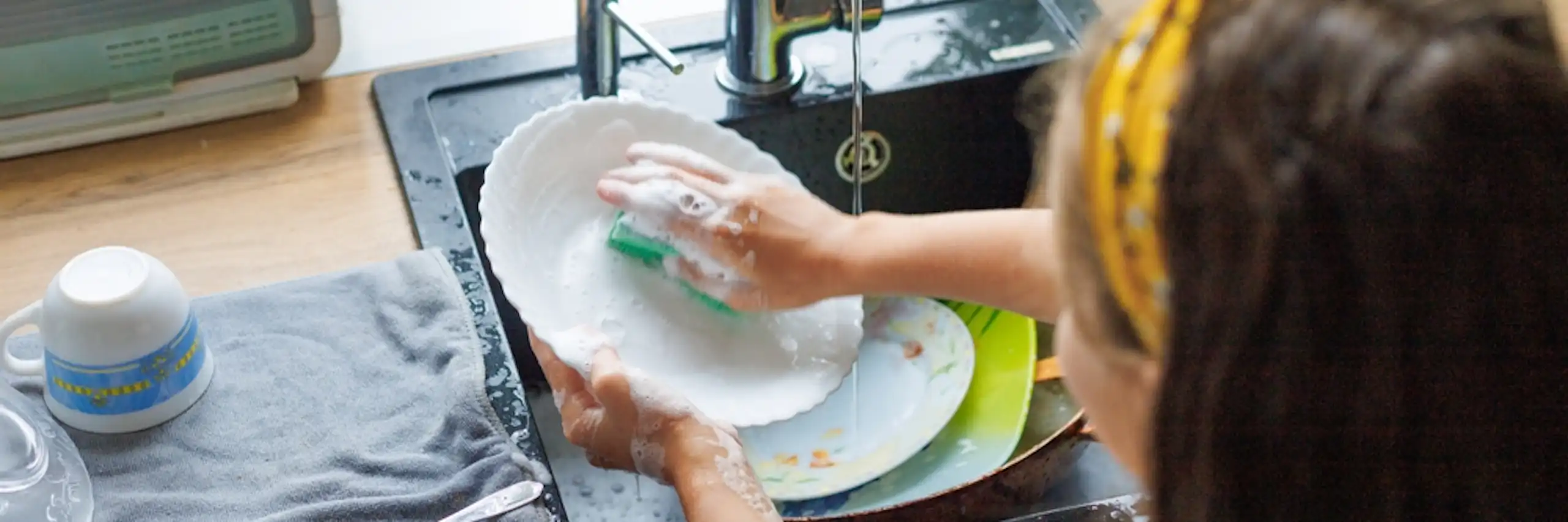 Une petite fille fait la vaisselle.
