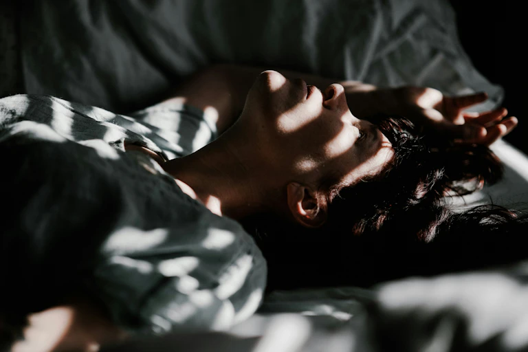 Un homme est couché dans un lit dans la pénombre.